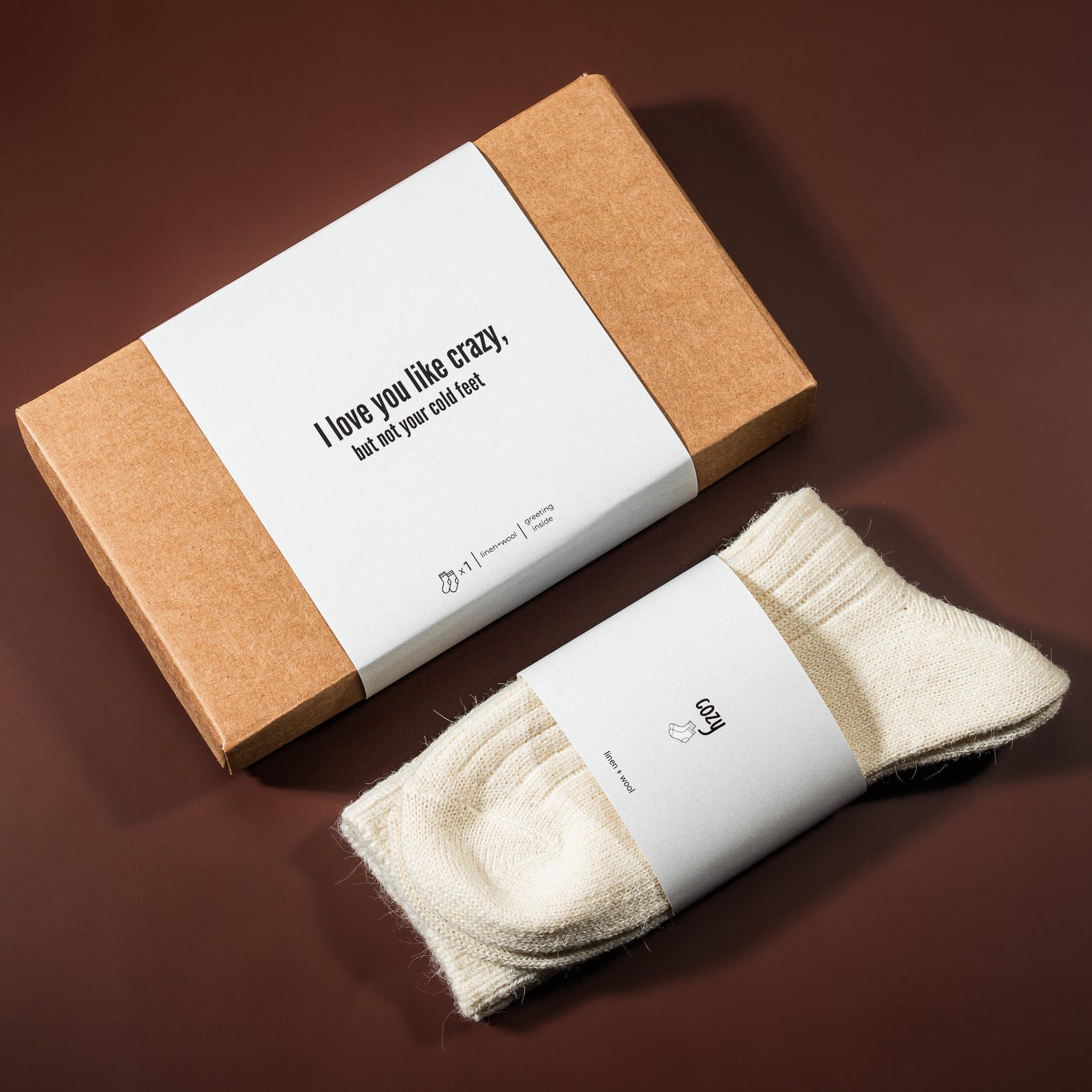 kalėdinė dovana: lino-vilnos kojinės, šalia padėta įpakavimo dėžutė