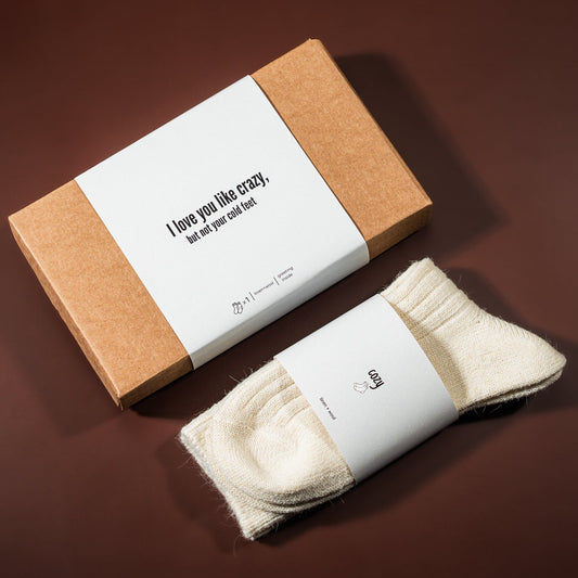 kalėdinė dovana: lino-vilnos kojinės, šalia padėta įpakavimo dėžutė