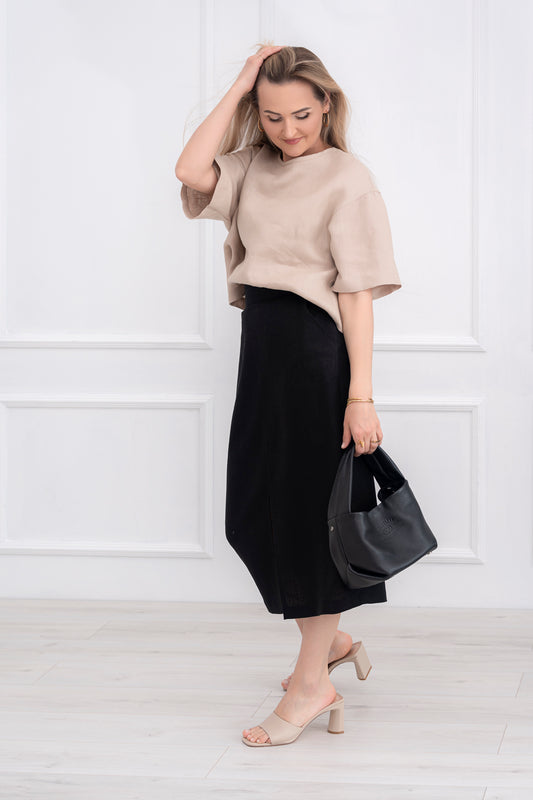 Lininė moteriška palaidinė, didinta, plati, trumpomis rankovėmis. Trumpa, laisvo modelio. Spalva - smėlio. Modelis taip pat vilki juodą lininį sijoną