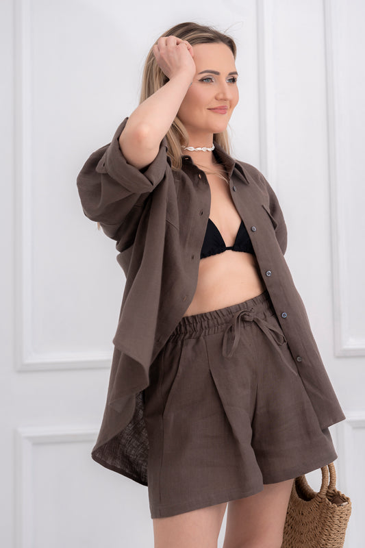 lininiai šortai moterims, trumpi, platūs, su klostėmis priekyje. Liemuo su guma ir raištuku, šortai su kišenėmis. Spalva - juoda. Modelis apsivilkusi ir derančius lininius marškinius.
