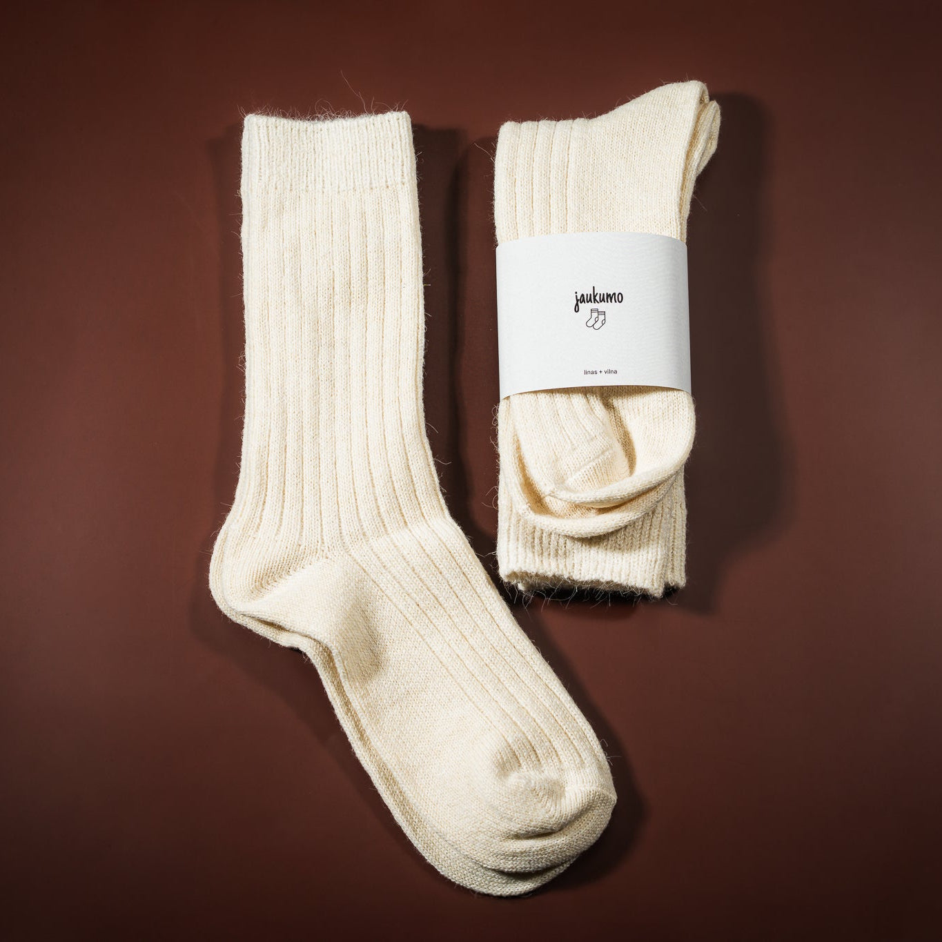Lino-vilnos kojinė, kreminės baltos spalvos, su etikete jaukumo kojinės, ir šalia padėtos kojinės ištiestos be etiketės