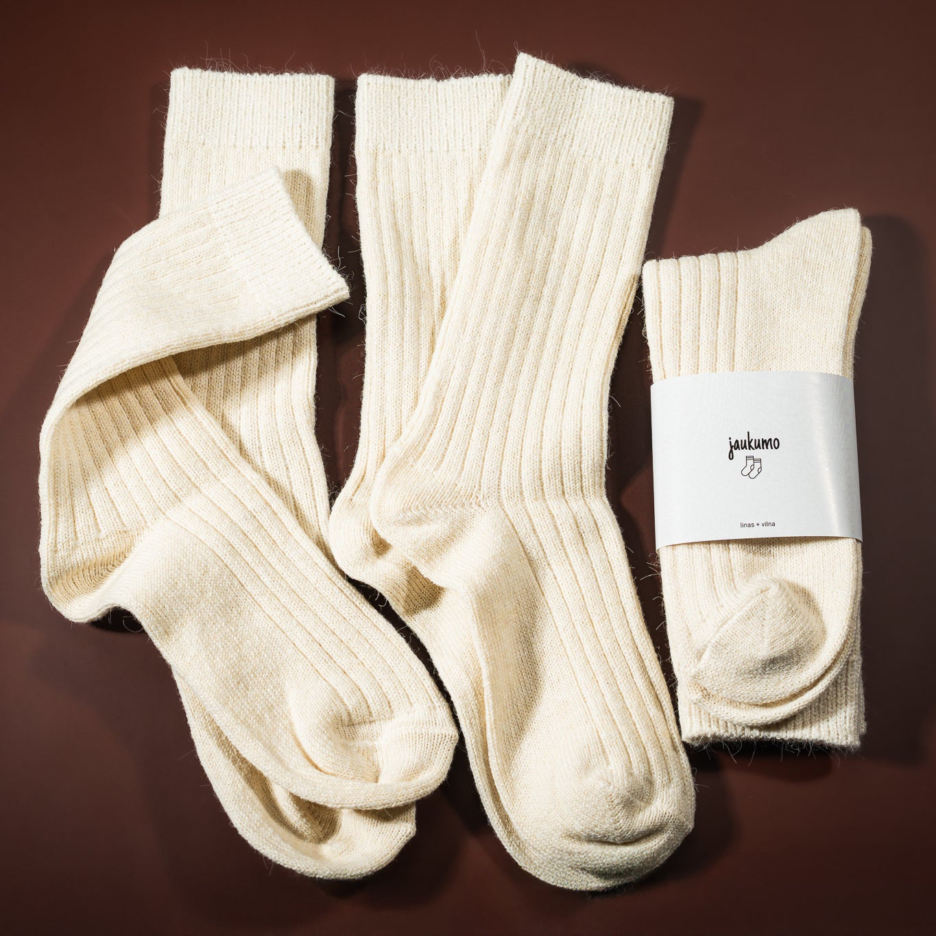 Lino-vilnos kojinė, kreminės baltos spalvos, su etikete jaukumo kojinės, ir šalia padėtos kojinės ištiestos be etiketės