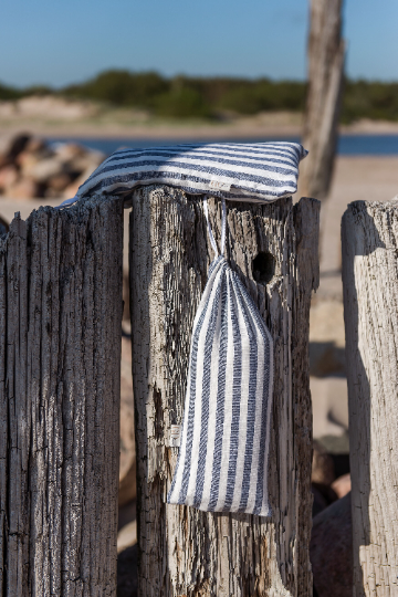 large beach towel folded and placed in a linen bag of the same color with a lacing