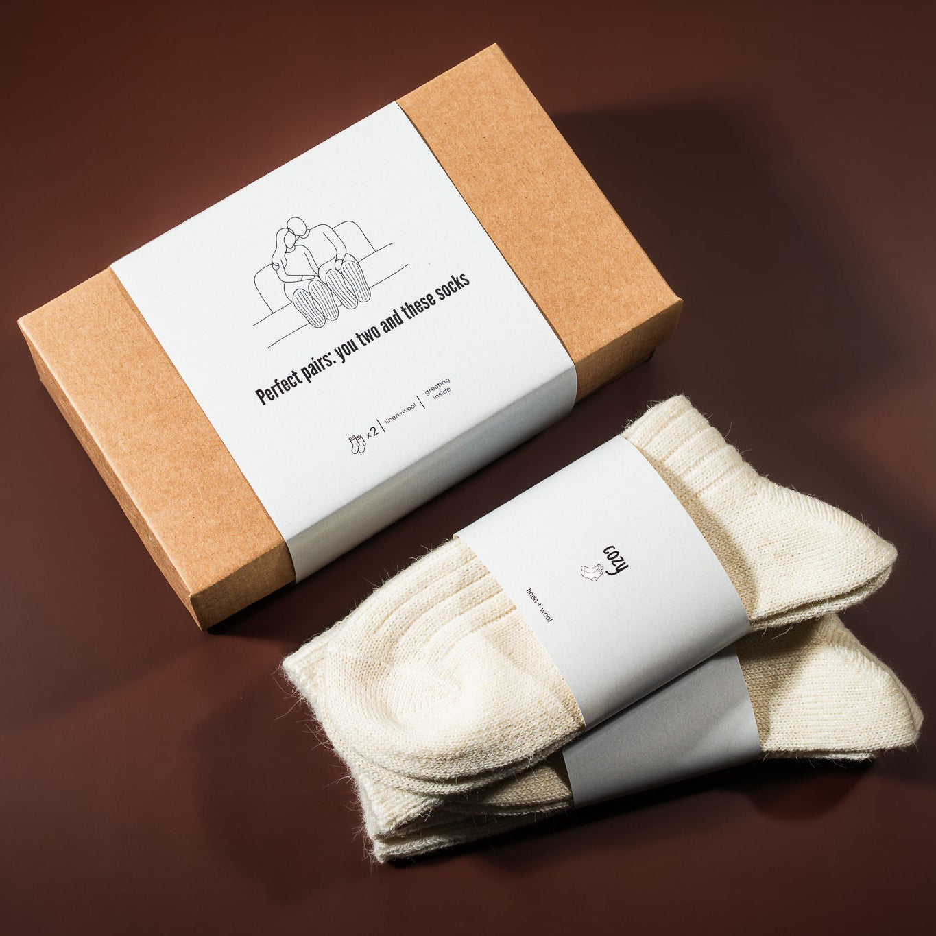 kalėdinė dovana: lino-vilnos kojinės, šalia padėta įpakavimo dėžutė 