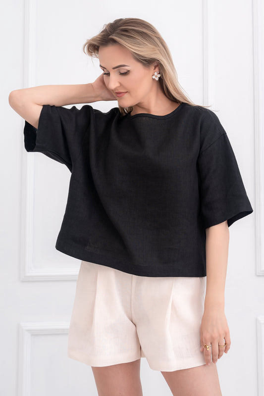 lininiai šortai moterims, trumpi, platūs, su klostėmis priekyje. Liemuo su guma ir raištuku, šortai su kišenėmis. Spalva - kreminė balta. Modelis apsivilkusi ir derančią lininę palaidinę.