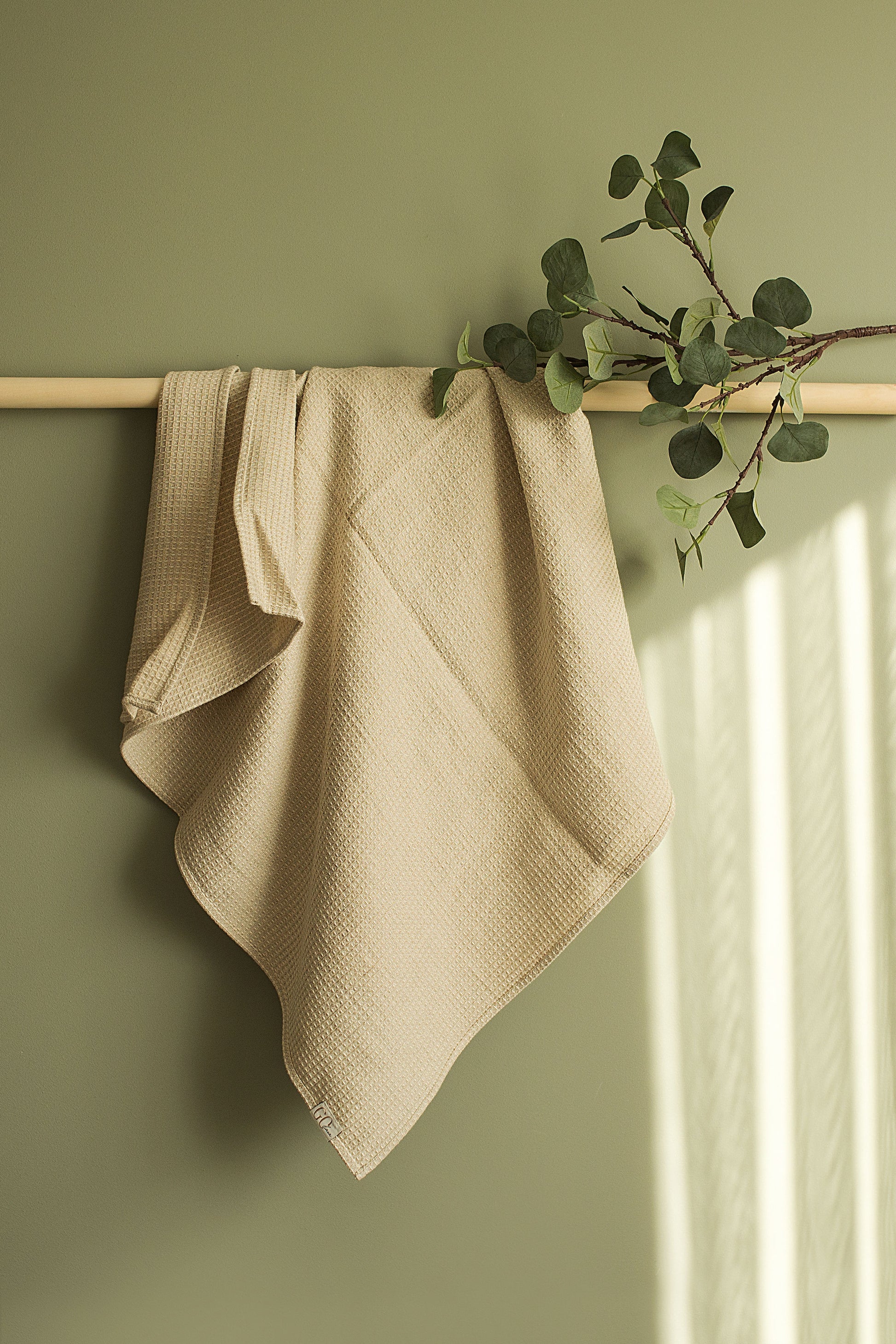 large bath towel hung on teh wooden towel holder